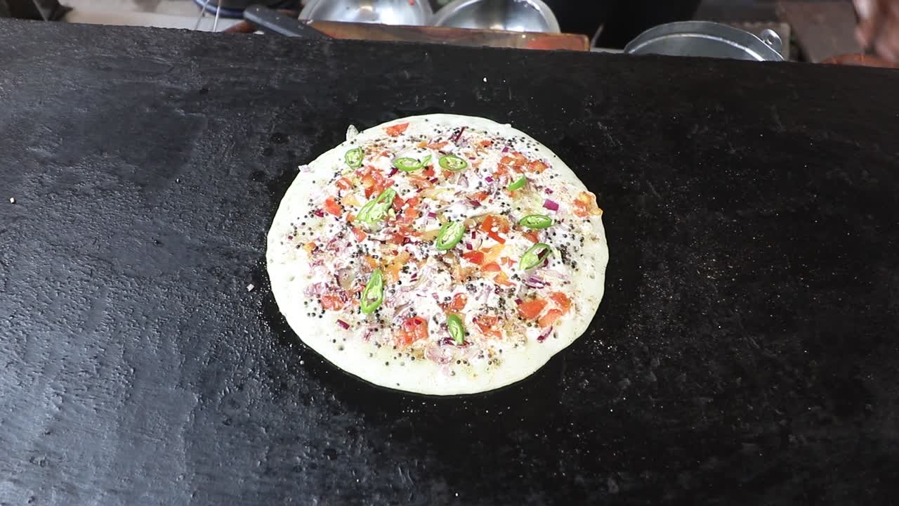 un vendedor de comida callejera cocina uttapam en su puesto de comida callejera en varanasi, india, el 9 de marzo de 2021