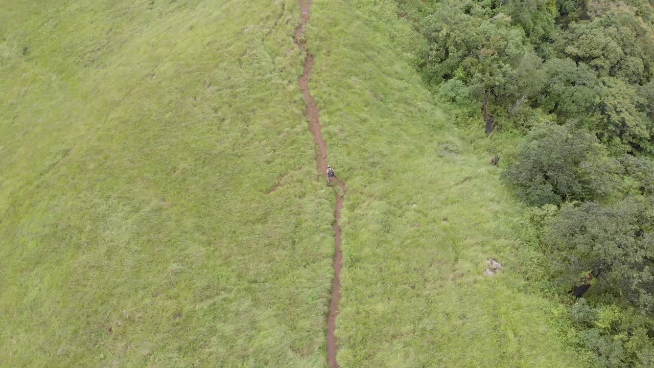 toma de seguimiento aéreo de 4k de un hombre indio de 25 años caminando en la cima del pico shirui, ukurul, manipur, india