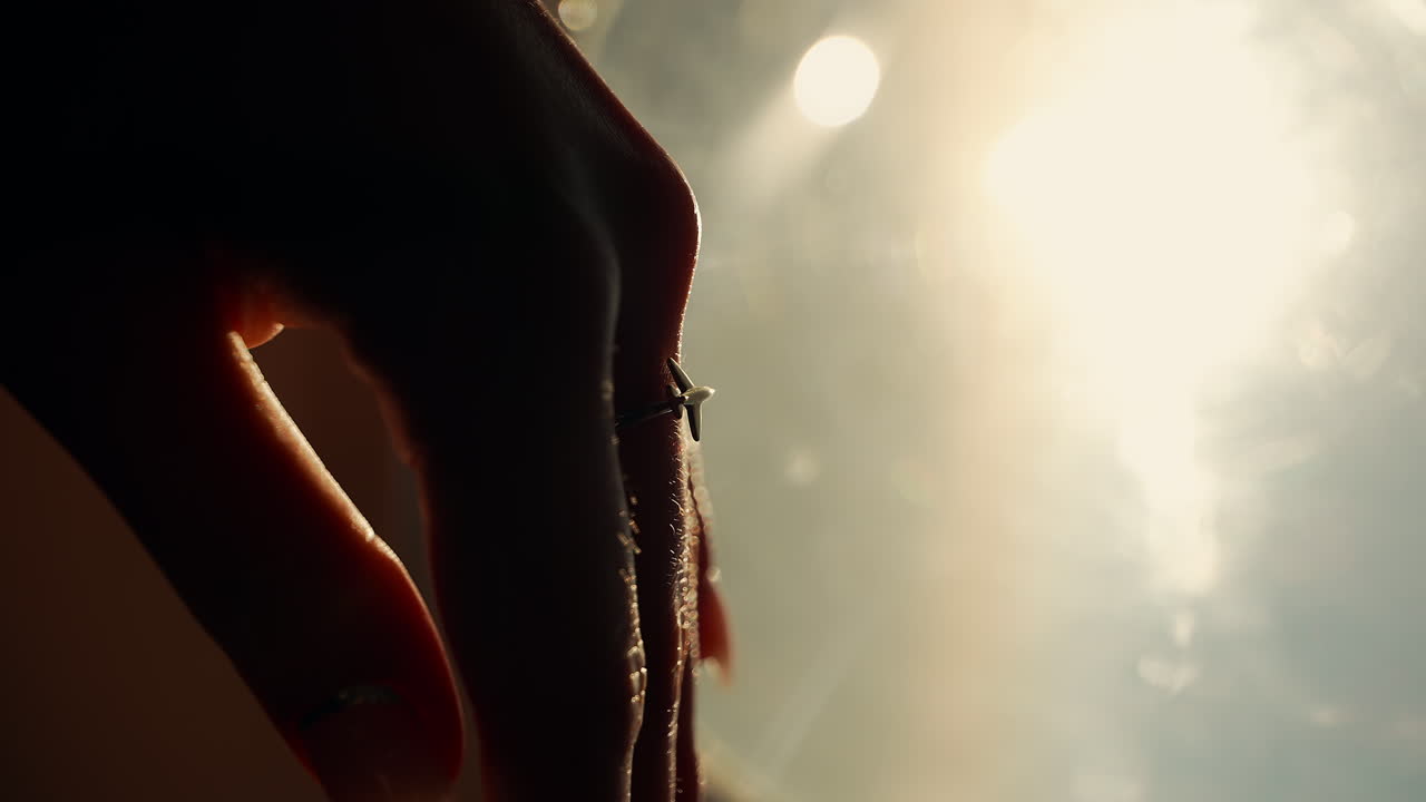 Mano di donna con anello a forma di aereo con luce intensa sullo sfondo.