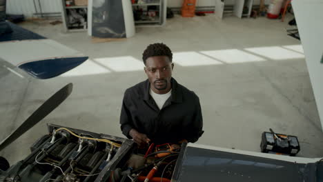 portrait of black mechanic examining aircraft engine with multimeter in hangar