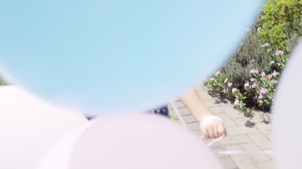 una niña rubia corriendo con globos en cámara lenta