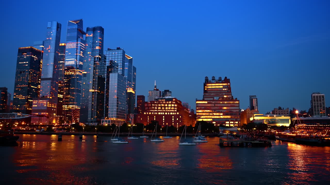 Toàn cảnh rộng lớn đường chân trời Hudson Yards nhìn ra sông Hudson. Khung cảnh rộng lớn các tòa nhà chọc trời phía Tây thành phố New York và thuyền buồm trên sông Hudson lúc chạng vạng với ánh đèn thành phố.