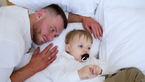 loving father lies near his little son sucking a pacifier. mother lies down beside her beloved child. top view.