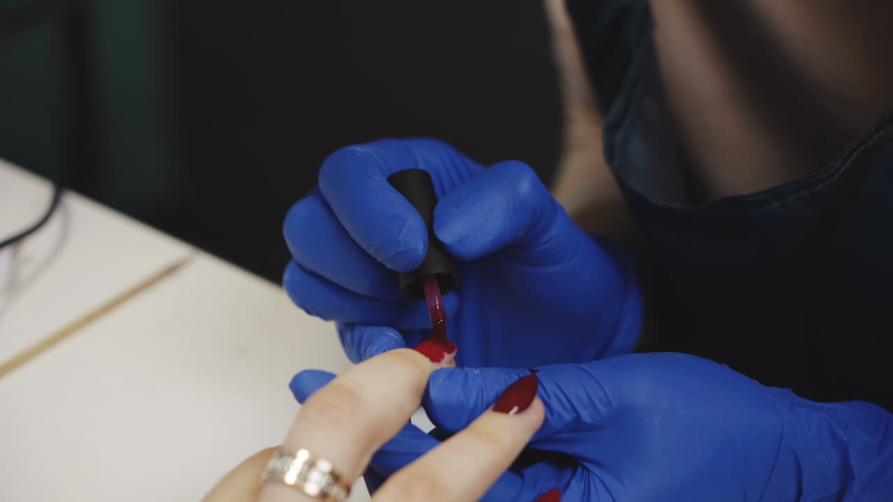 una mujer se pinta las uñas.