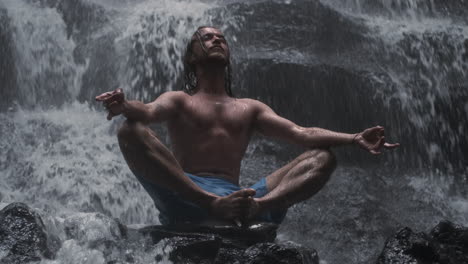 Junger-Mann-Meditiert-Unter-Wasserfall.