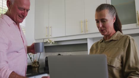 Caucasian-senior-couple-drinking-coffee-together-in-the-kitchen-at-home