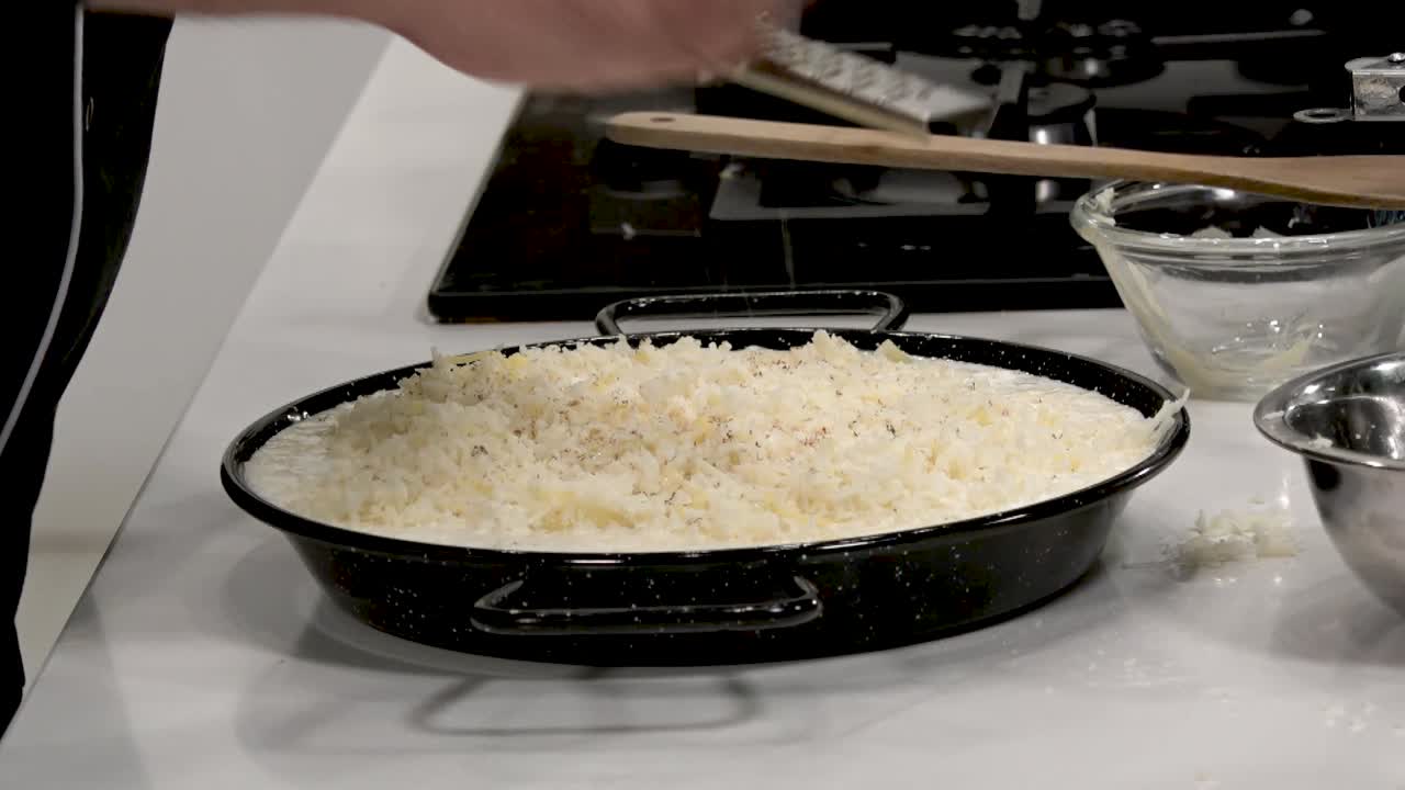 A chef prepares rice using precise techniques in a contemporary kitchen. The rice is gently fluffed and seasoned, showcasing a careful cooking process