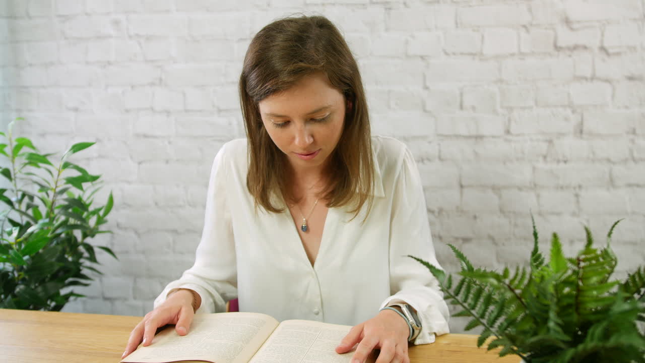 Uma jovem lendo um livro antigo e vintage sentada em uma escrivaninha