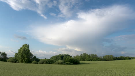 Zeitraffer-Von-Weißen-Wolken,-Die-über-Eine-Grüne-Landschaft-Rollen-Und-Sich-In-Einen-Sturm-Verwandeln