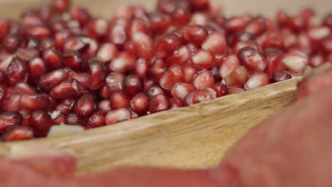 slow pan across pomegranate seeds inside of wooden plate juicing and using fresh ingredients and fresh whole pomegranates