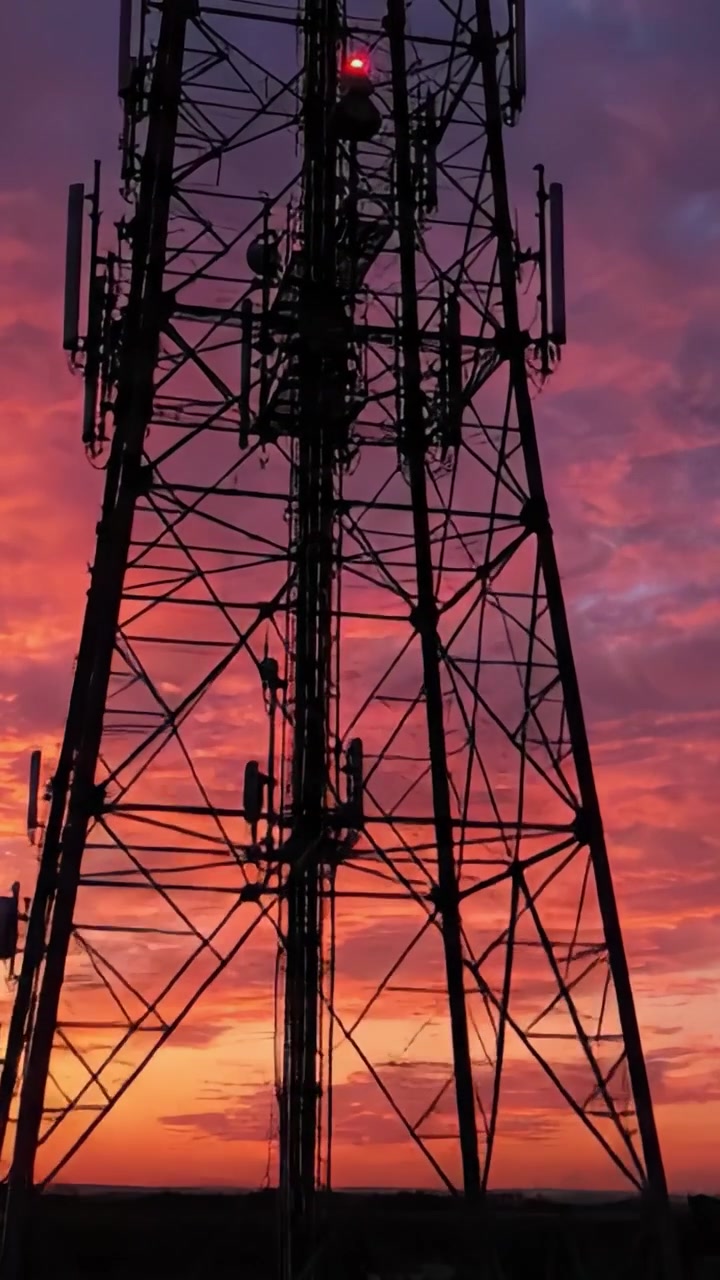 Splendida silhouette al tramonto di una torre di comunicazione contro un cielo colorato illuminato da vivaci sfumature di arancione, rosa e viola