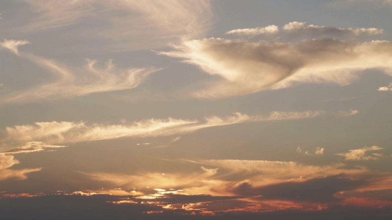 Sinking sun painting western sky orange and red, highlighting wispy clouds and silhouette