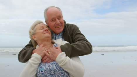 vista frontal de una vieja pareja caucásica abrazándose en la playa 4k