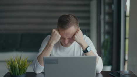 frustrated young man sitting in front of his laptop after reading bad news, says no. finance crisis