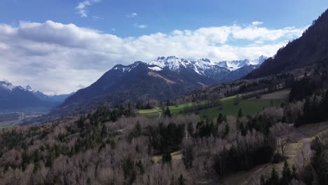 drone fly above forest mountain road with snow covered summits in background.nature landscape in austria, europe