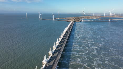 aerial slow motion shot of the open eastern scheldt storm surge barrier and wind turbines on a beautiful sunny day