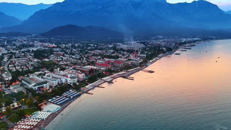 lots of people rest at the beach line of the mediterranean sea. scenic view on the resort town kemer in turkey at sunset. huge rocks at backdrop