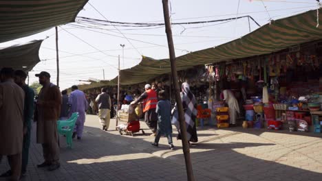 bustling islamabad market scene showcasing people engaged in lively haggling and shopping for essential groceries from street vendors and stalls.