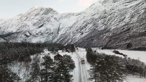 vista aérea de un camión de carga conduciendo por una carretera asfaltada nevada en canadá en invierno con montañas rocosas en el fondo