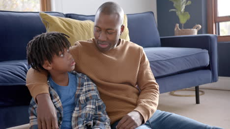 african american father and son embracing, talking and high fiving at home, slow motion