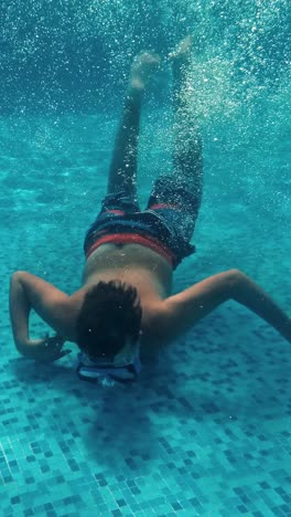 young guy swims underwater in a swimming pool