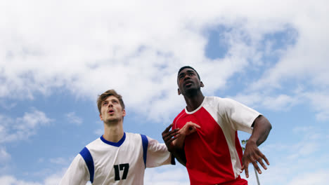 two football players jumping to strike a ball