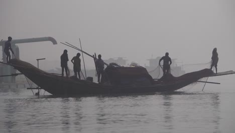 silhouette mid-shot of fishermen preparing nets for fishing in the river