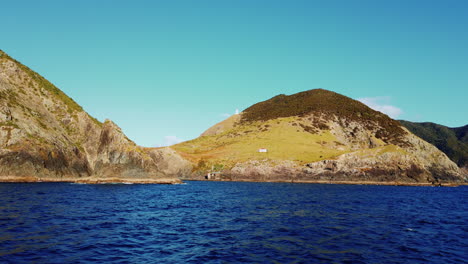 distant view of lighthouse on a hill with surrounding blue waters in the bay of islands, new zealand - wide shot