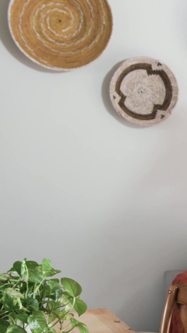 Video verticale: Inquadratura inclinata che mostra un pothos in un vaso bianco su un tavolo di legno per rivelare cesti intrecciati.