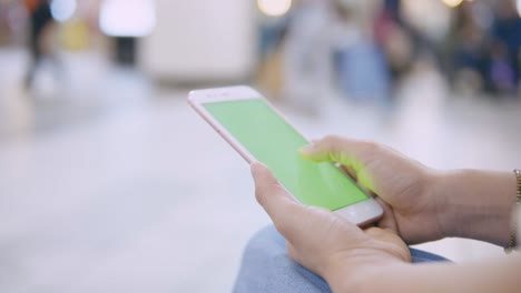 woman using smartphone with green screen on the street.