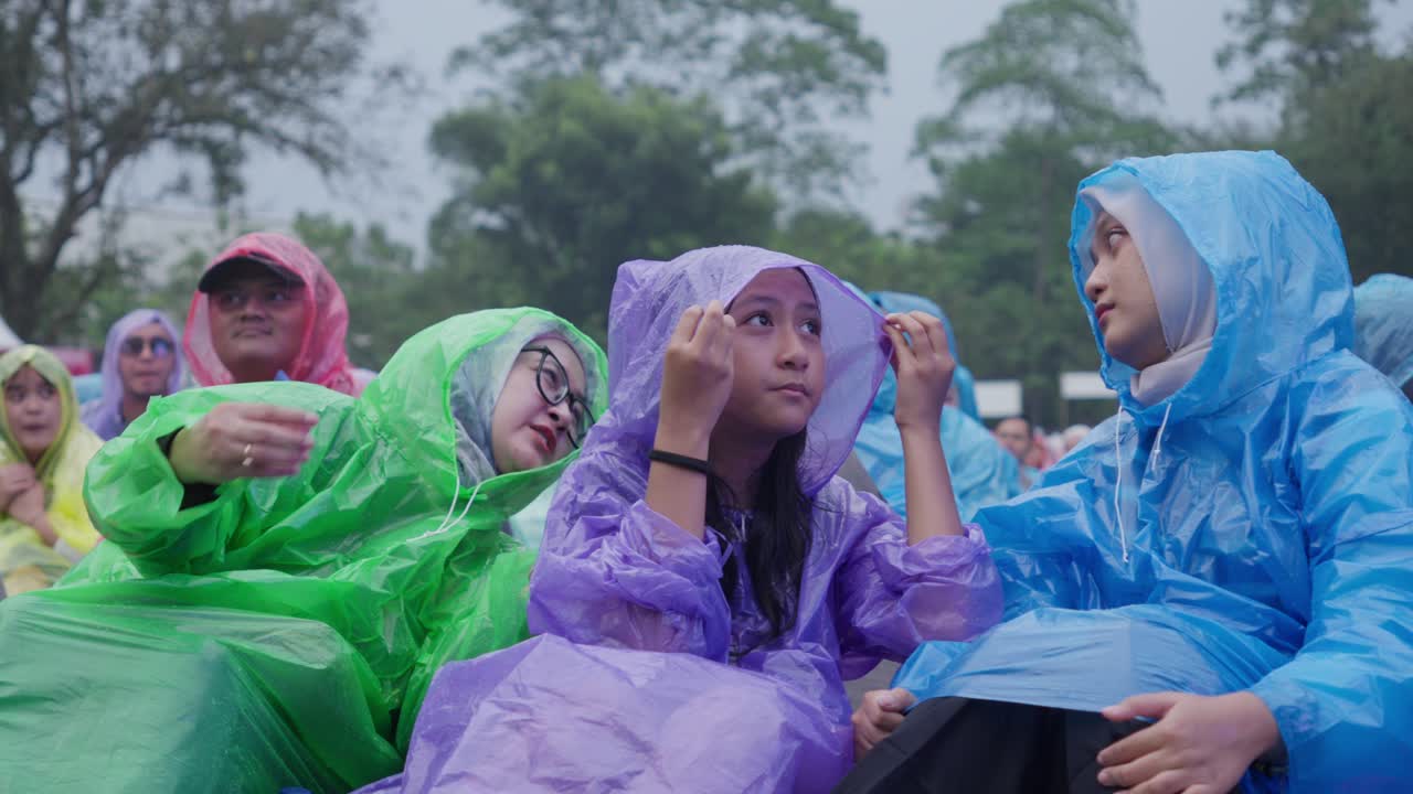 Indonesians in raincoats enjoy a concert at Kebun Raya Bogor