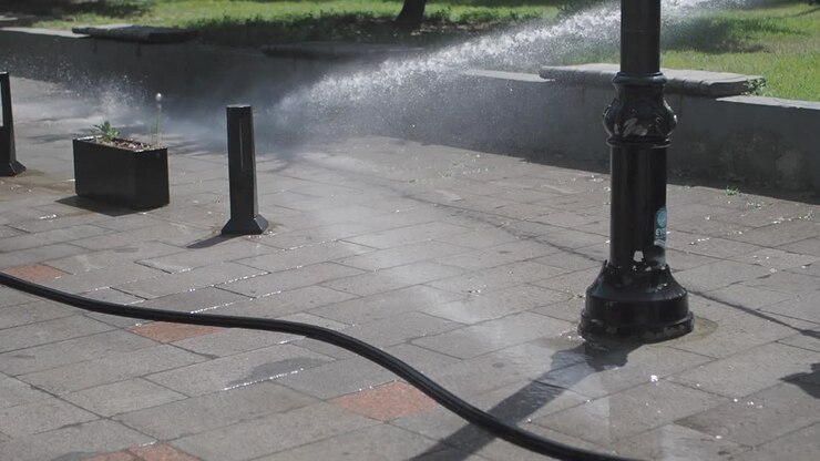 Pulizia di una strada cittadina con una manichetta d'acqua