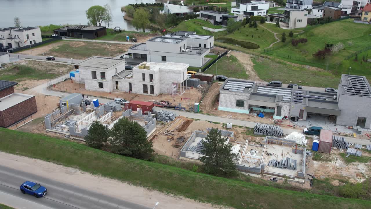 Drone arcs backward revealing residential construction progress in Vilnius