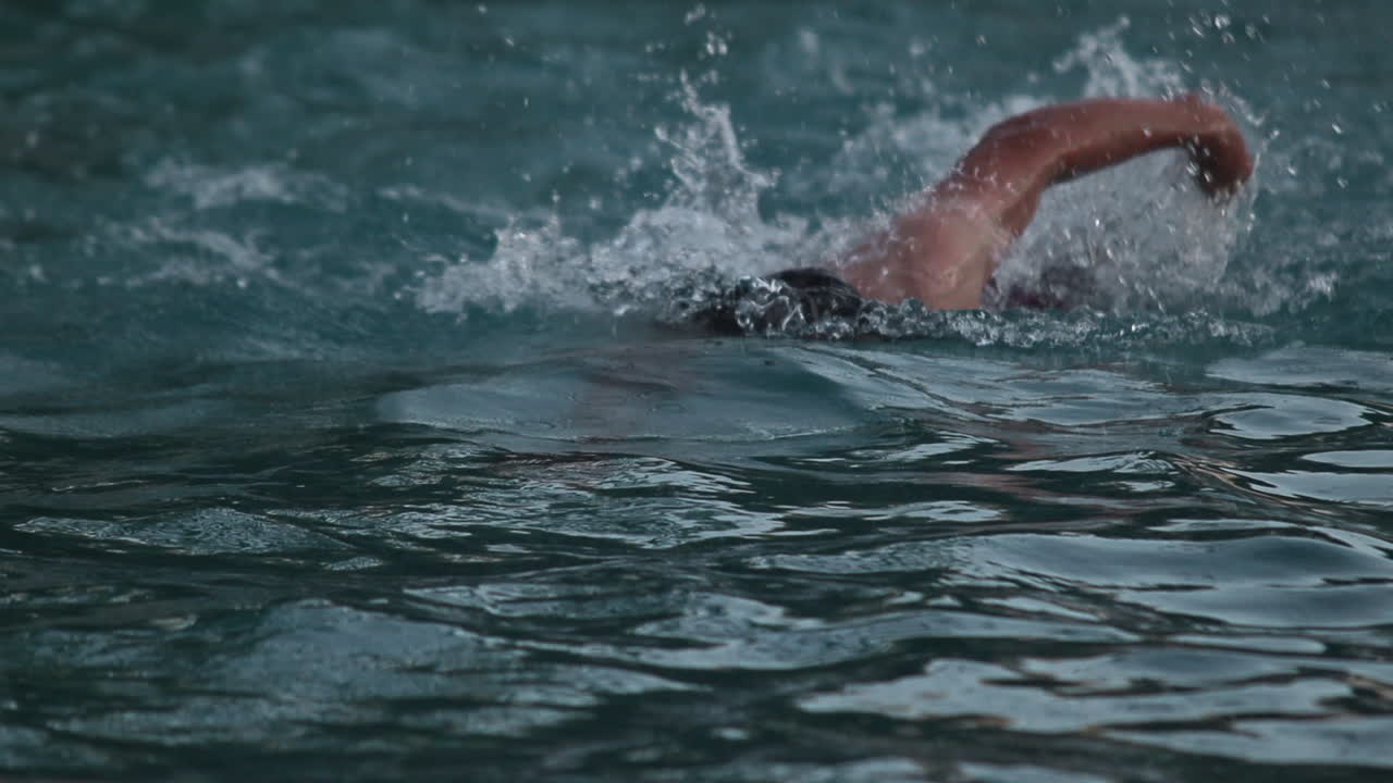 hombre caucásico nadando estilo libre en el agua, cámara lenta, hacia la cámara
