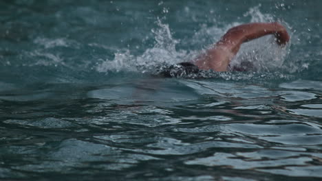 hombre caucásico nadando estilo libre en el agua, cámara lenta, hacia la cámara
