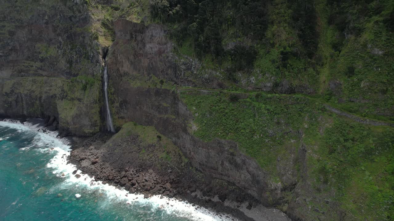 olas que chocan contra la costa rocosa de la isla de madeira con una cascada en portugal