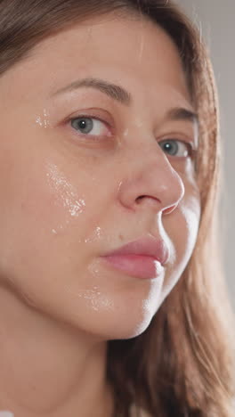 mujer masajea áreas problemáticas de la cara con una herramienta de microcorriente. mujer morena señala un dispositivo de masaje sobre la cara en el baño en el fondo en cámara lenta