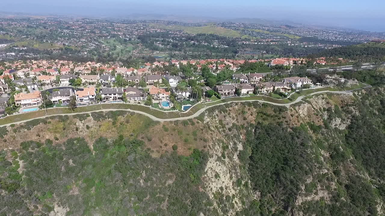 Slow motion rotating aerial drone shot flying over luxury homes in Laguna Niguel, Orange County, California that face Aliso Creek