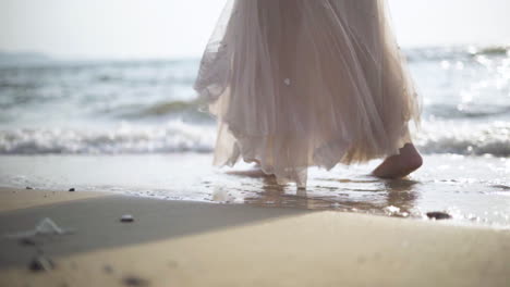 low angle .women walking barefoot by the beach while the sun sets.waves at sunset.slow motion.slow motion