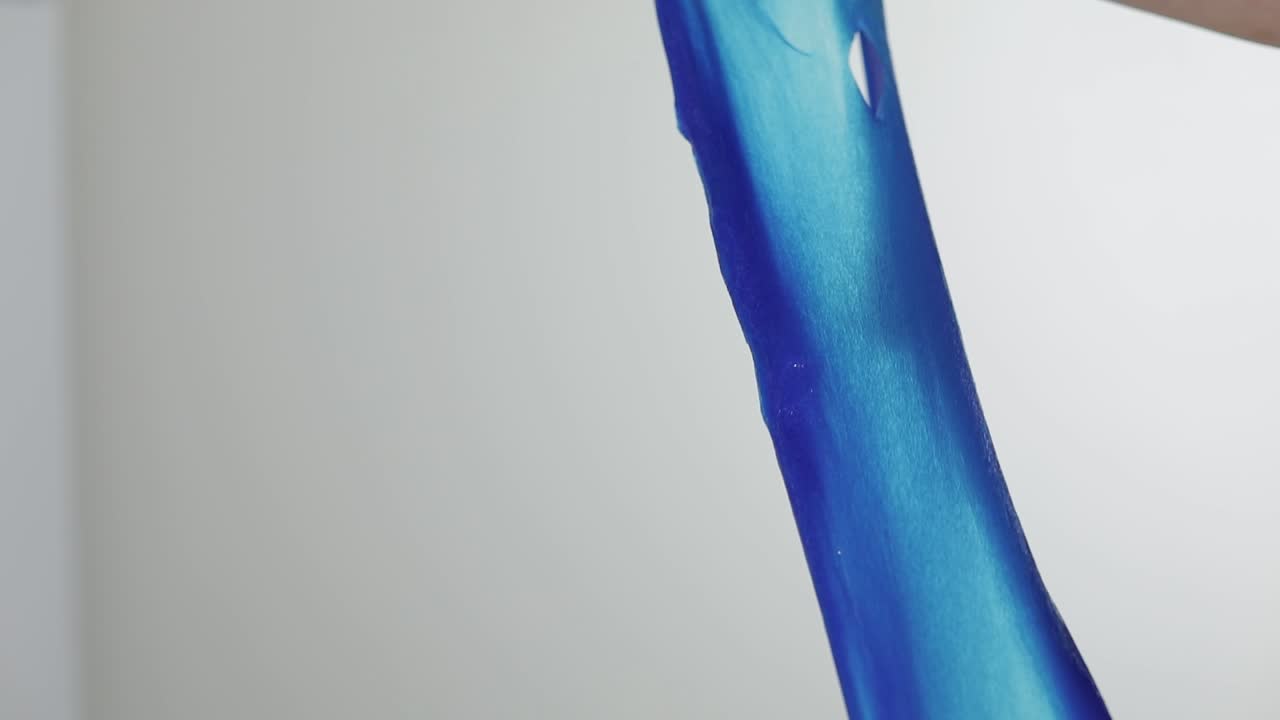 이상하게 만족스러운 파란 슬림 적적한 물질로 놀고 있는 여성의 손.