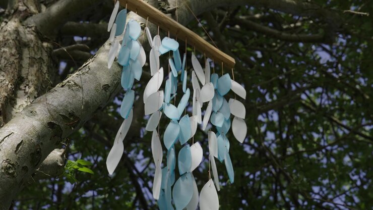 Campanelli a vento che fluttuano nel vento su un albero verde, primo piano al rallentatore.