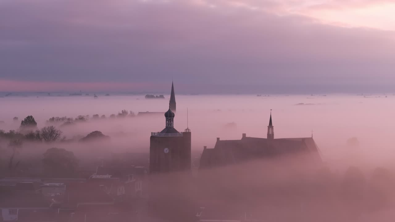 Workum by med kirke i tåge ved solopgang, Holland