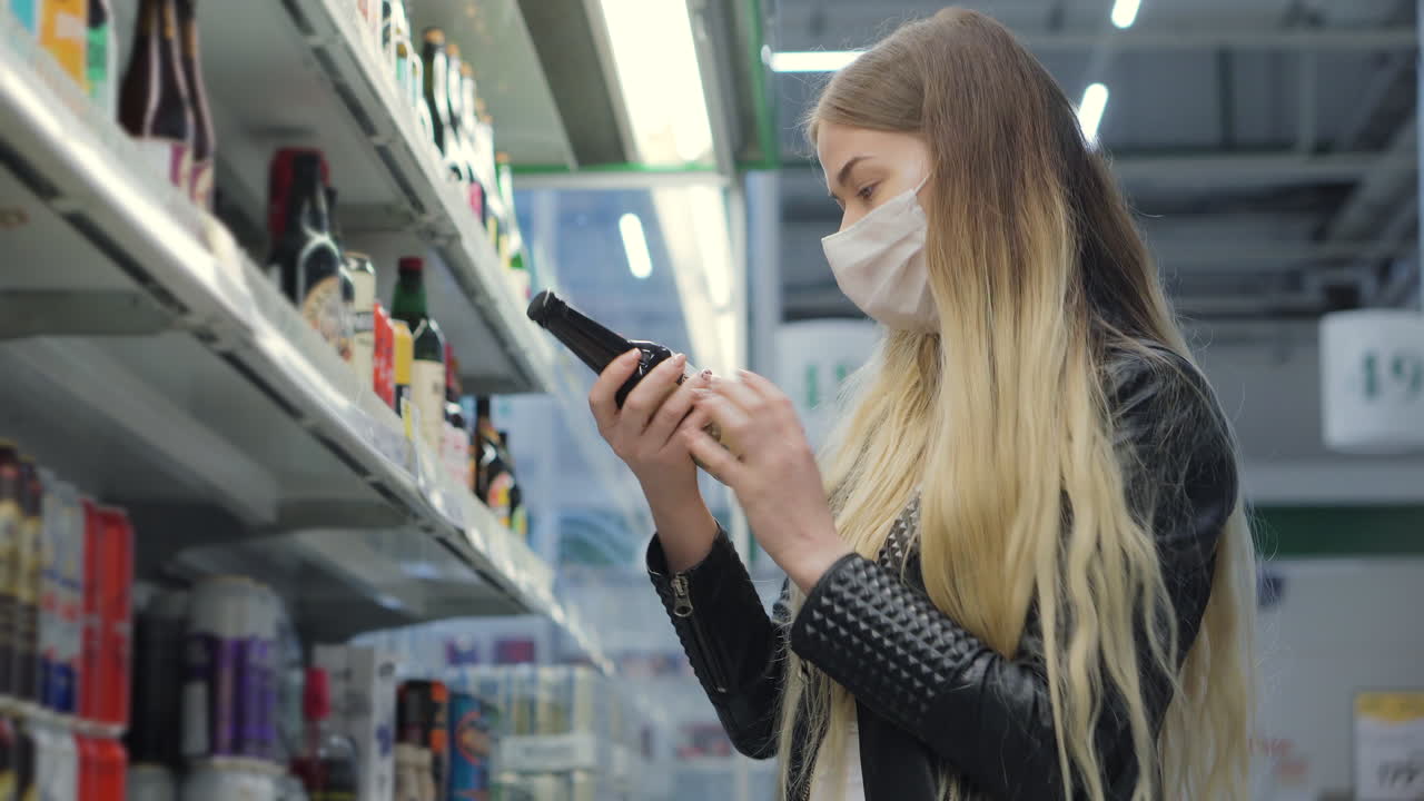 마스크를 쓰고 슈퍼마켓에서 맥주를 구입하는 여자