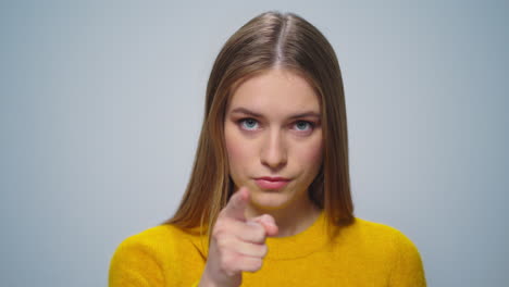 portrait of ambitious woman pointing finger on camera on grey background.