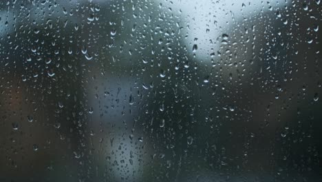 raindrops falling down glass window trees in background close up dark