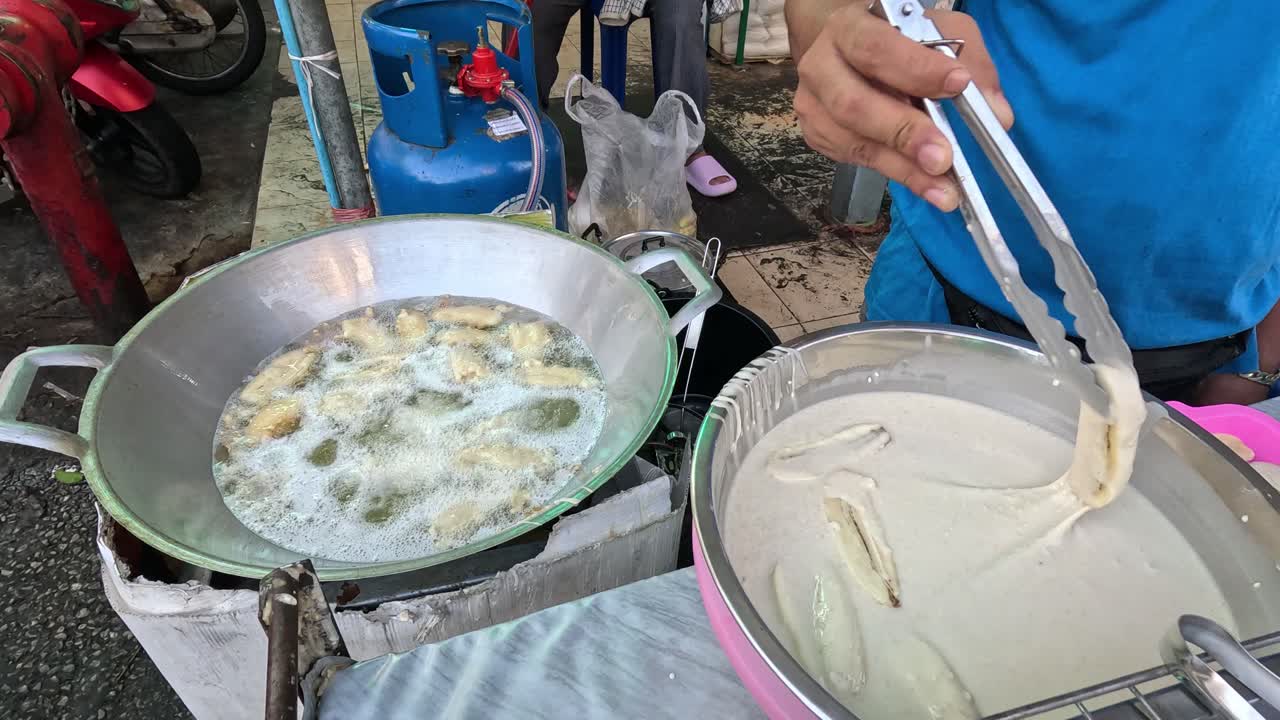 거리 판매자 가 뜨거운 기름 에 바나나 를 기