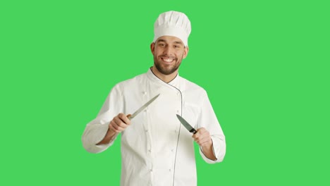 mid shot of a handsome smiling chef sharpening his knifes. background is green screen.