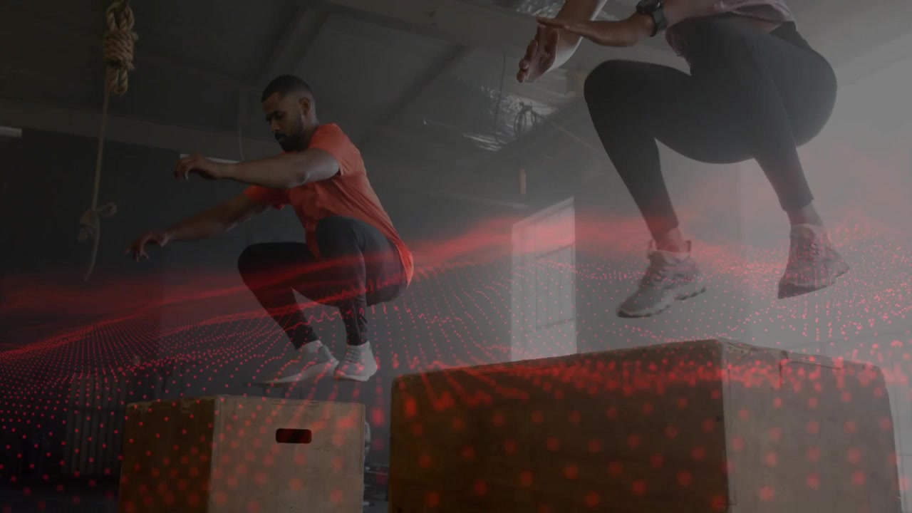 Man and woman swinging arms starting synced box jumps for fitness power, red grid overlaying bodies