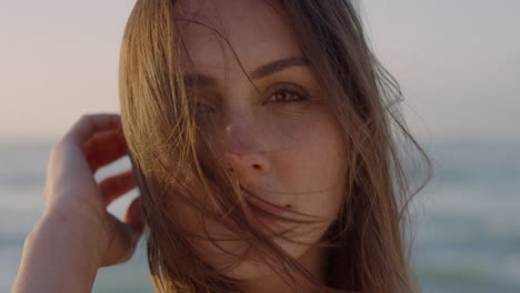 close up portrait of happy young woman smiling enjoying summer vacation running hand through hair on windy beach seaside