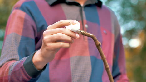 putting marshmallow on a wooden stick to hold it above the fire